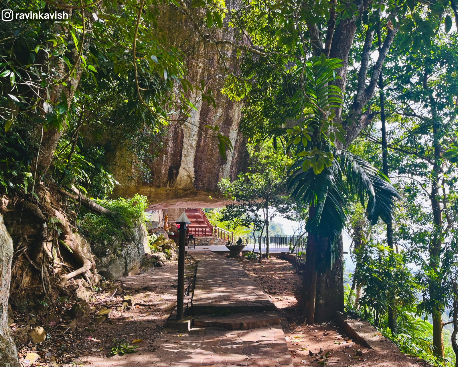 Distant view of the rock-formed shelter at Rakkiththa Kanda Rajamaha Viharaya with surrounding hills and greenery