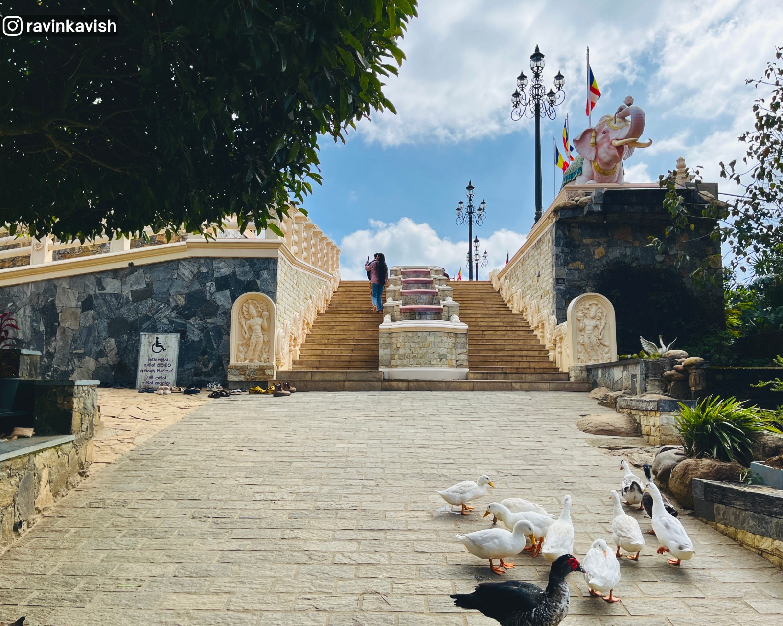 Main entrance and courtyard of a Buddhist monastery in Ella featuring distinctive elephant statues leading into the grounds showcasing Sri Lankas religious heritage