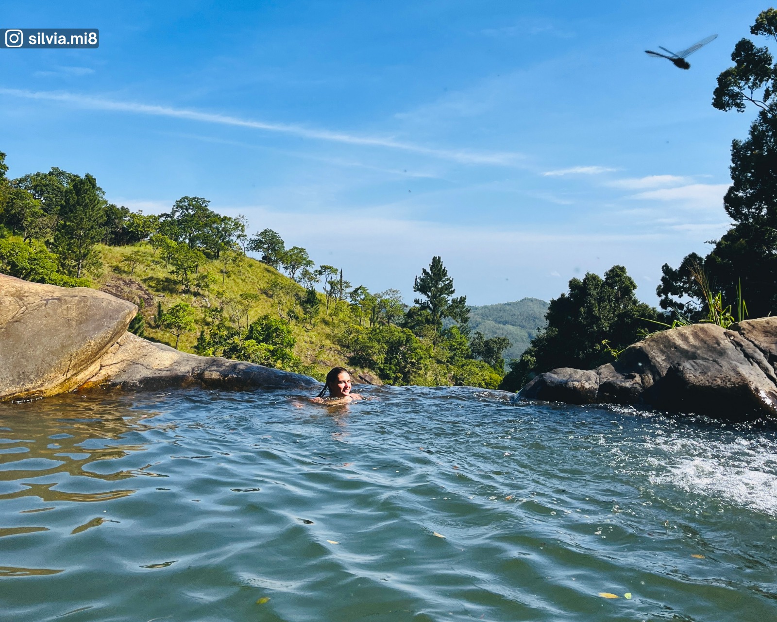 Natural pool at the top of Upper Diyaluma Falls, where the waterfall begins, with surrounding greenery, sky, and a dragonfly hovering above