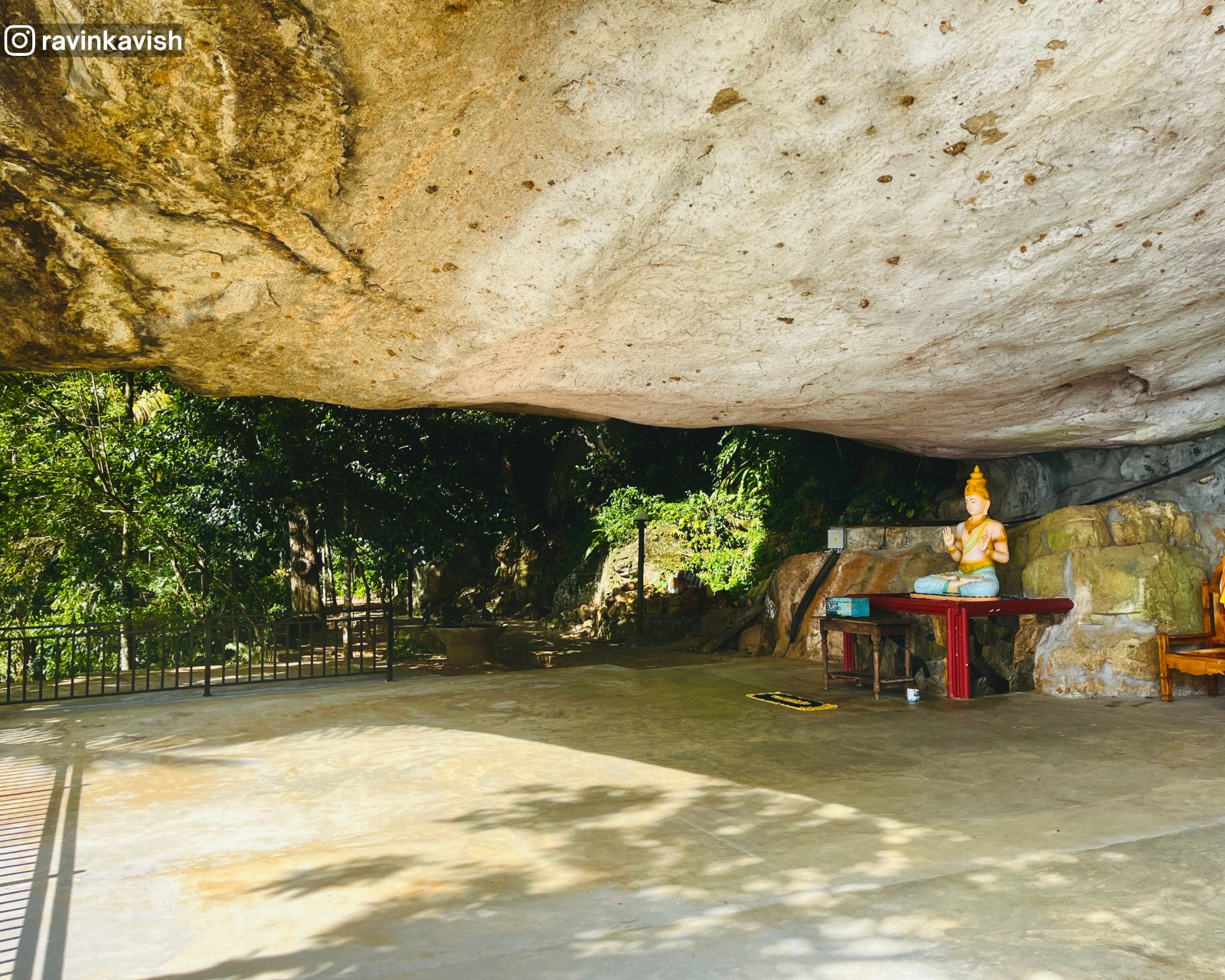 Natural rock formation at Rakkiththa Kanda Rajamaha Viharaya forming a roof that shelters the area, with the new Bodhisattva statue beneath it