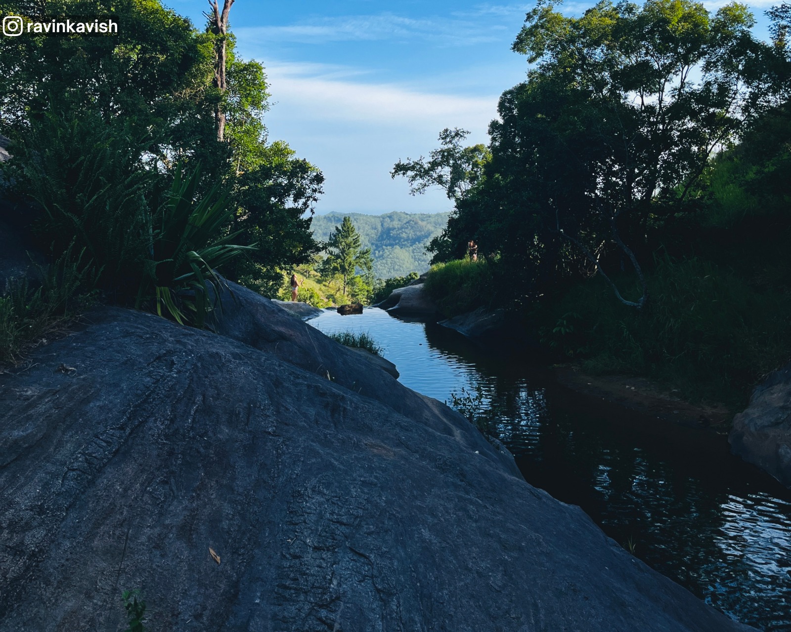 Open stream of water flowing through a rock formation, forming Upper Diyaluma Falls at the end