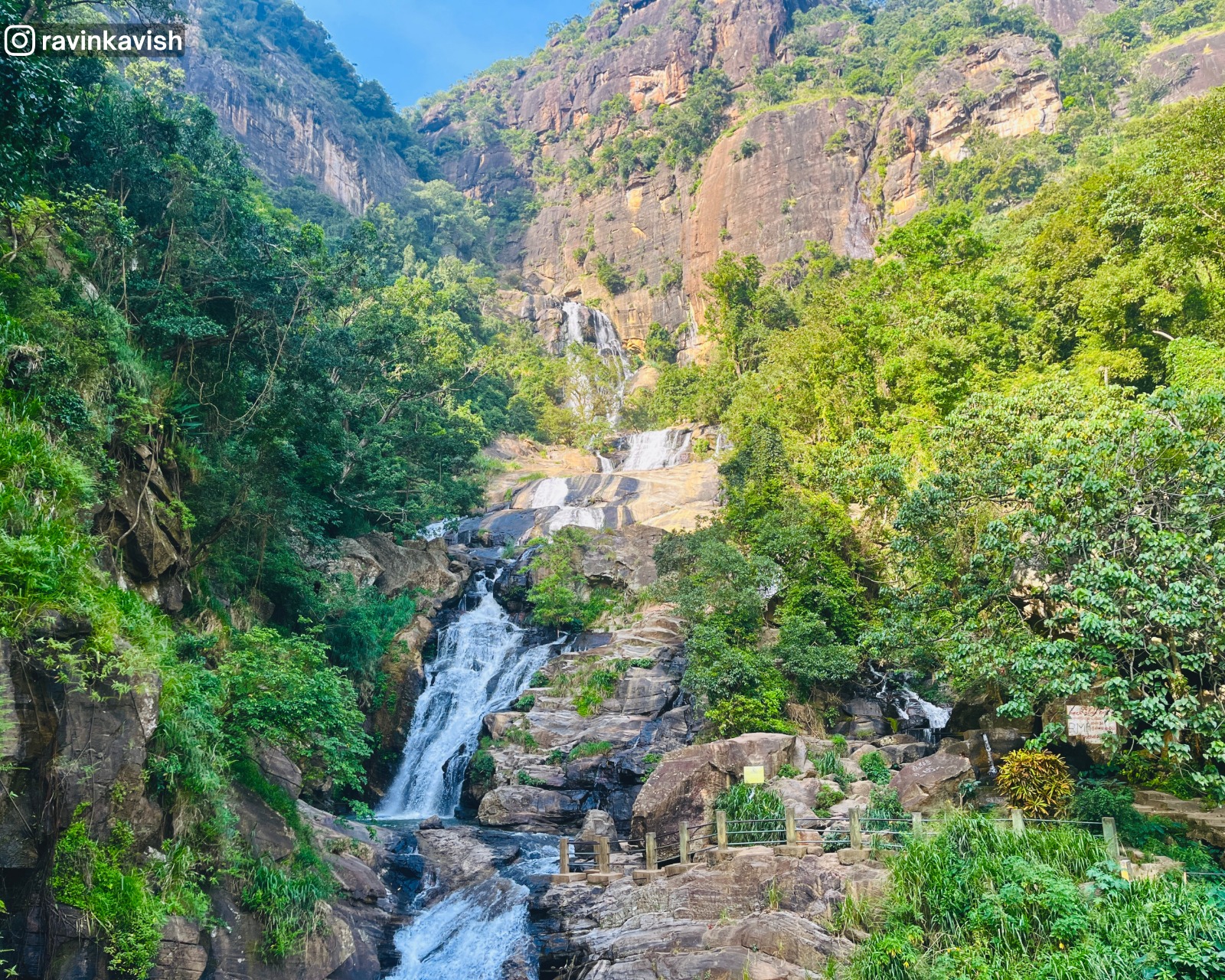 Ravana Waterfall cascading down the rocky cliffs surrounded by lush greenery near Ella, Sri Lanka, with mist rising from the base