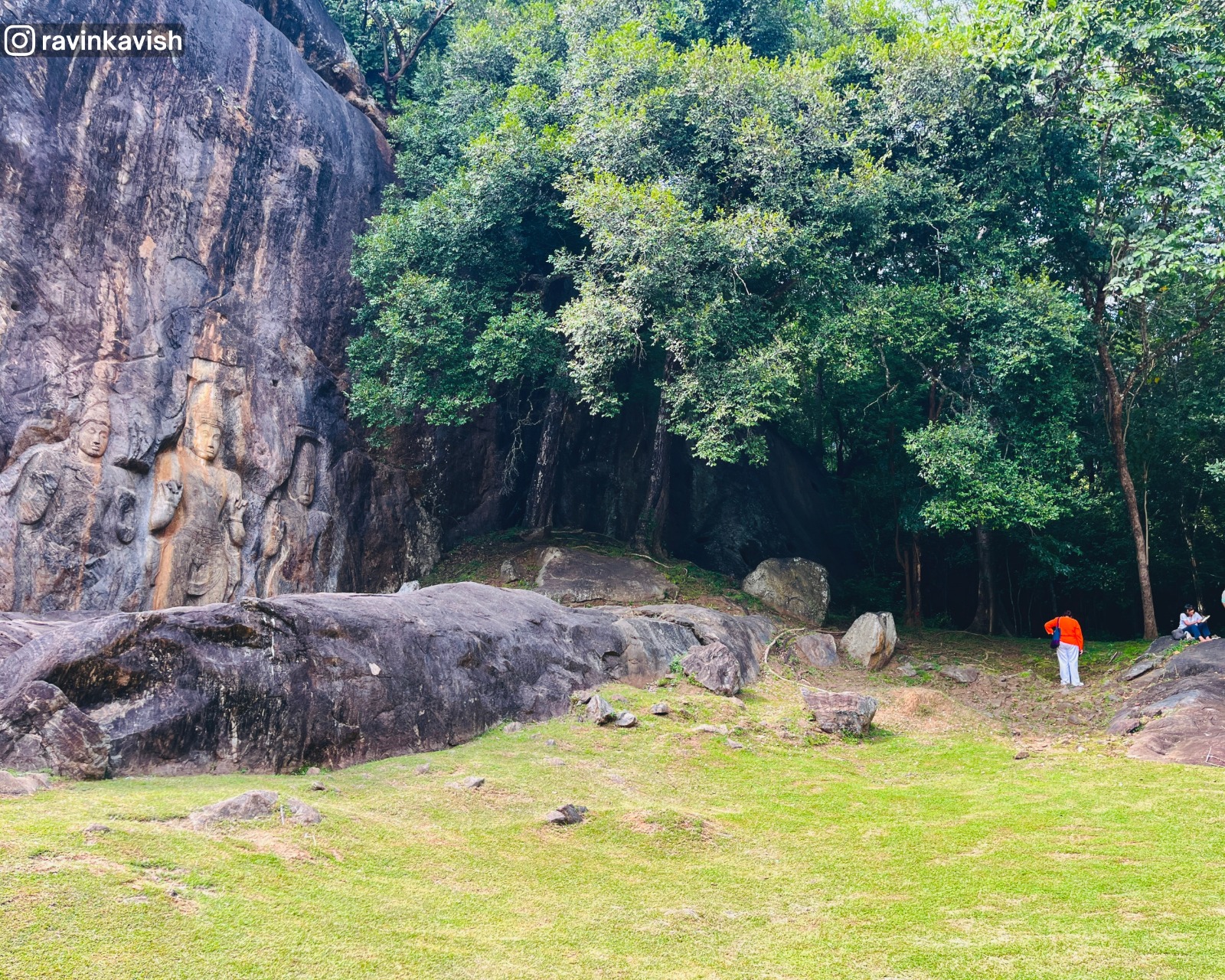 Right side of the Buduruwagala showing the three carved figures, with the massive rock face and surrounding forested landscape