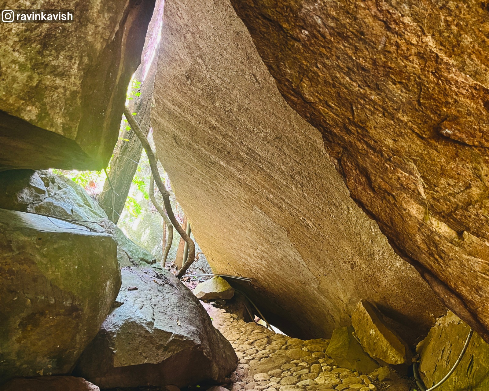 Rock-covered temple passage at Rakkiththa Kanda Rajamaha Viharaya, where massive natural boulders form a shaded walkway along the cave temple path