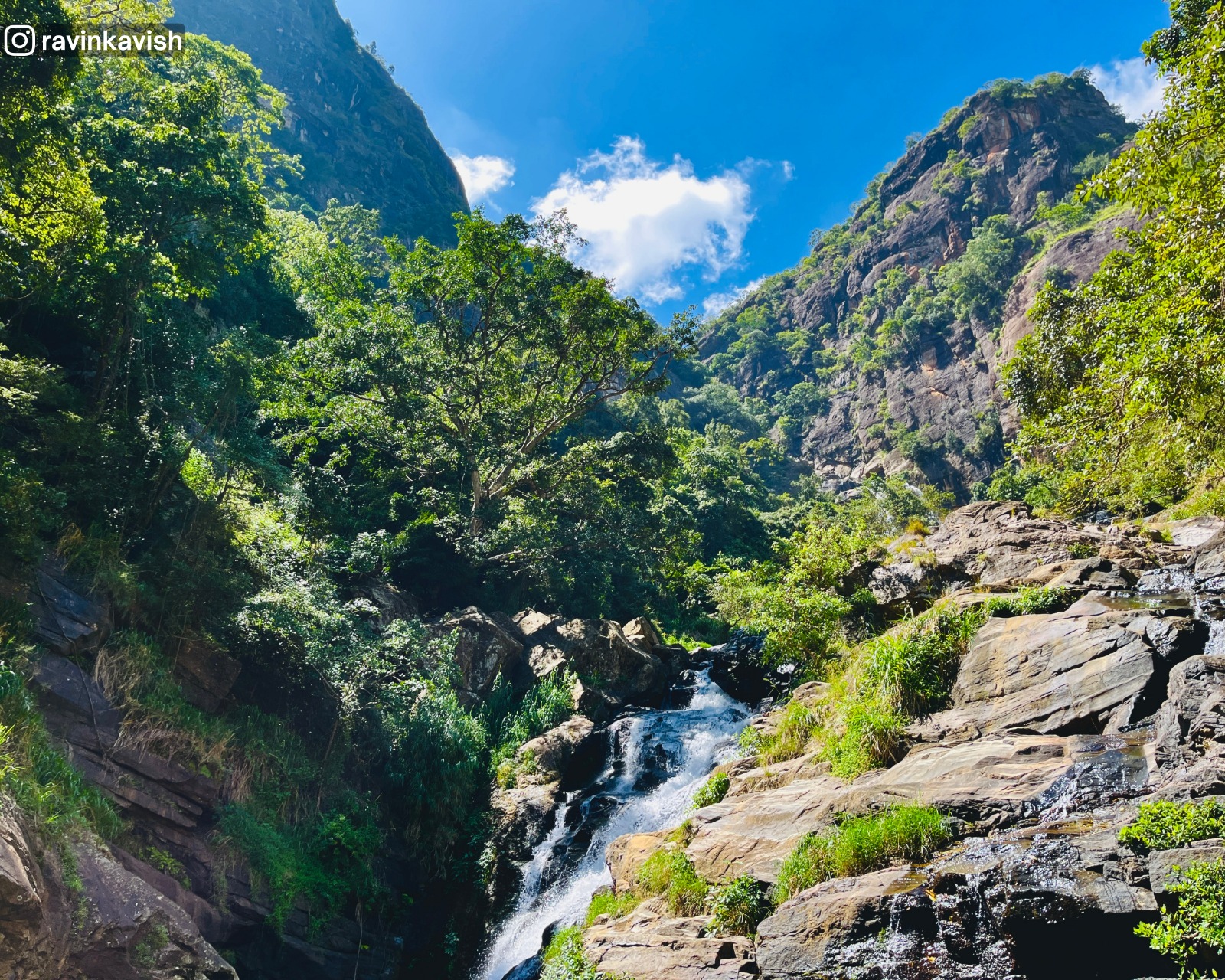 The famous Ravana Waterfall in Ella with surrounding rock formations and overgrown trees showcasing Sri Lankas natural beauty