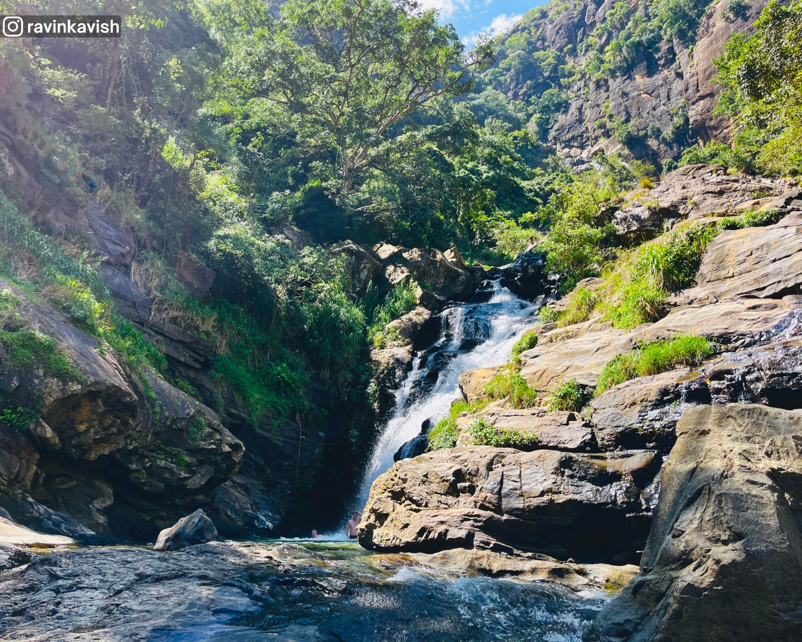 The famous Ravana Waterfall in Ella with rock formations, grass, and trees showcasing Sri Lankas natural beauty