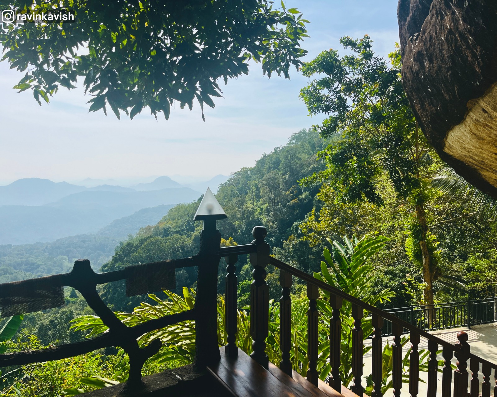 View from the fence at Rakkiththa Kanda Rajamaha Viharaya overlooking distant mountains and hills, with a small part of the natural rock shelter roof visible