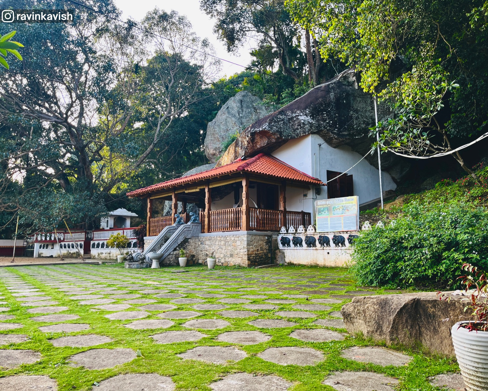 View just inside Ravana Royal Temple, showing the terrace garden, image house, sacred Bo tree, surrounding rock formations, and greenery