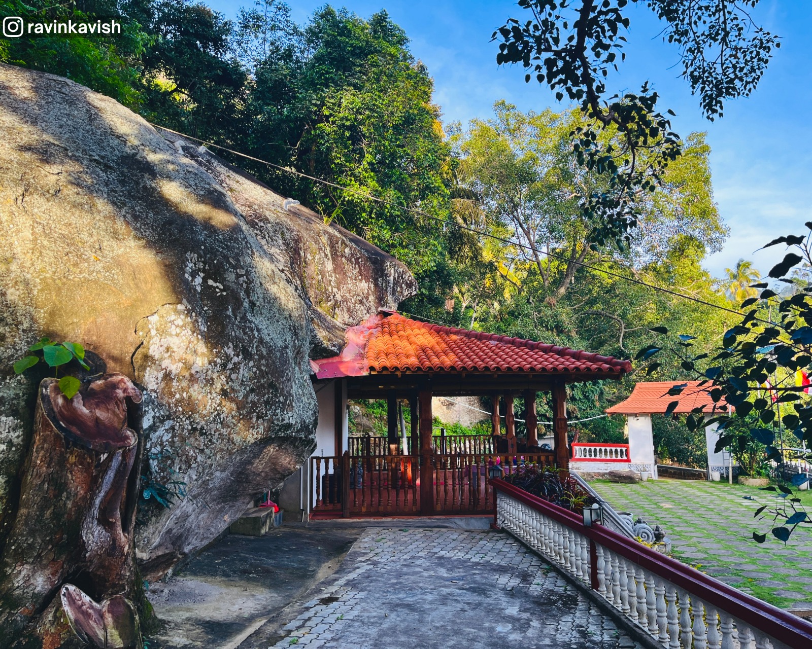 View of the image house at Ravana Royal Temple, near Ella, seen from beside the sacred Bo tree, with surrounding greenery and temple grounds