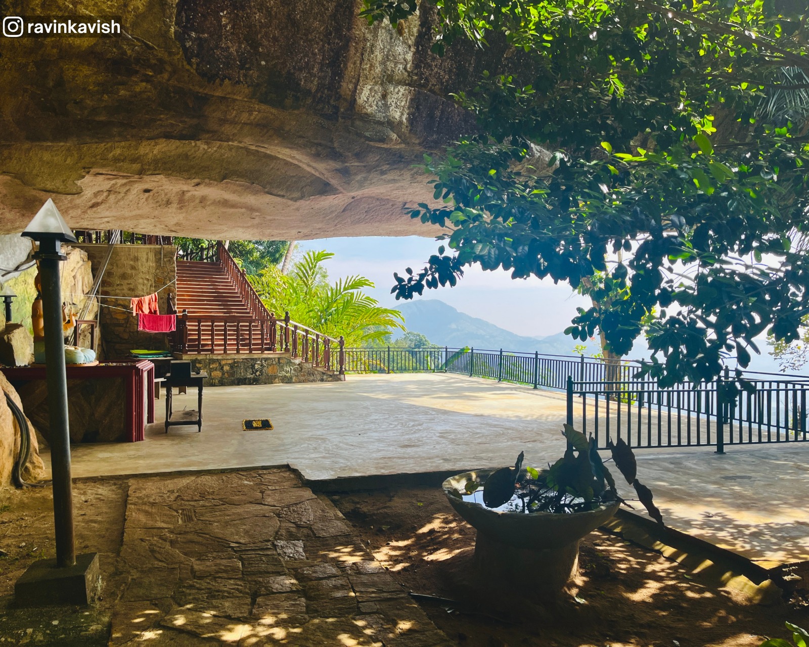 View of the surrounding hills and greenery seen through the natural rock shelter at Rakkiththa Kanda Rajamaha Viharaya with a new Bodhisattva statue