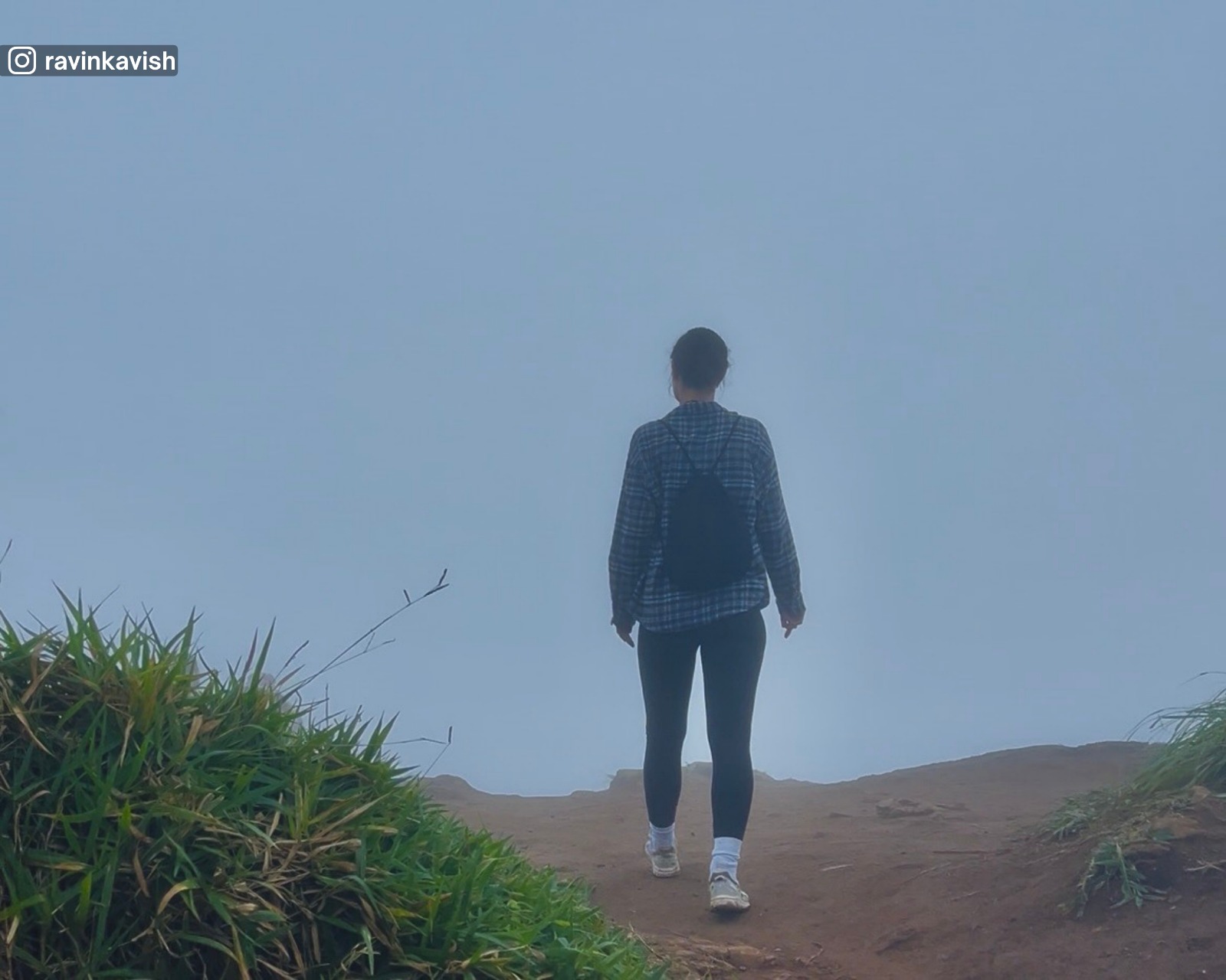 Walk at the summit of Little Adam’s Peak during fog with only the foreground dirt and grass visible as the fog obscures all distant views
