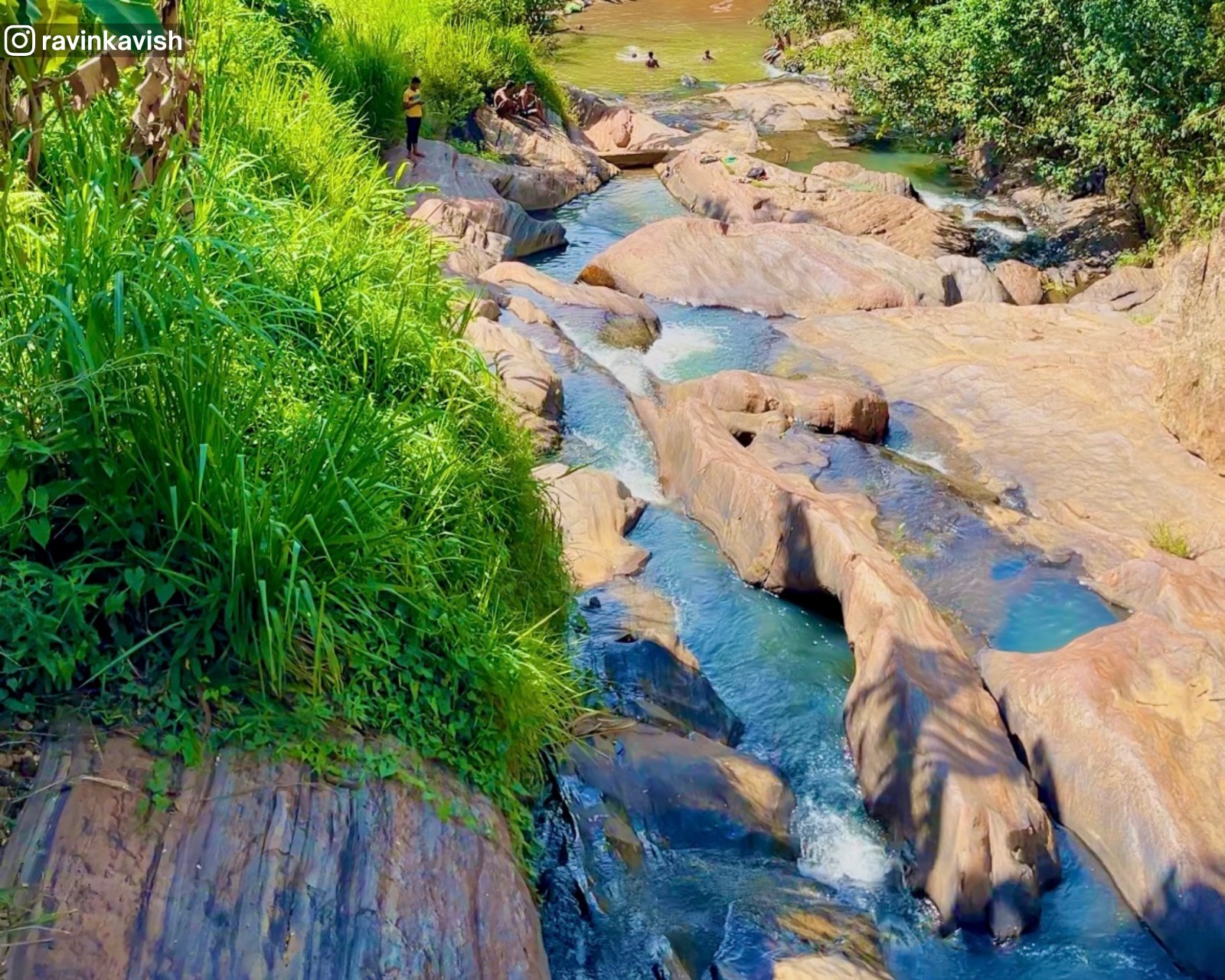 Water stream flowing through rocks along the hiking trail of Ella Rock, surrounded by lush greenery