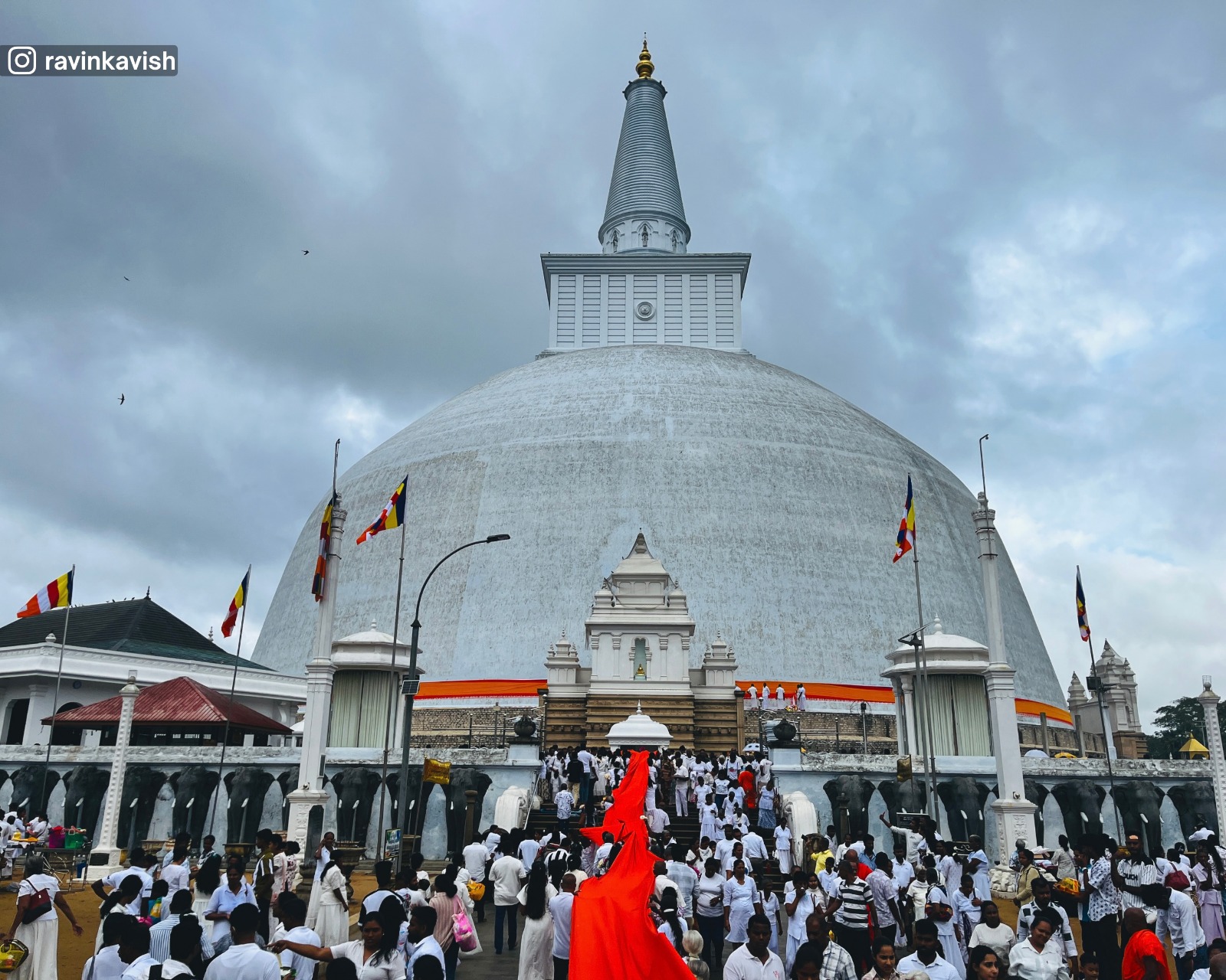 Devotees gathered around the white Ruwanwelisaya Stupa during a Buddhist ceremony in Anuradhapura