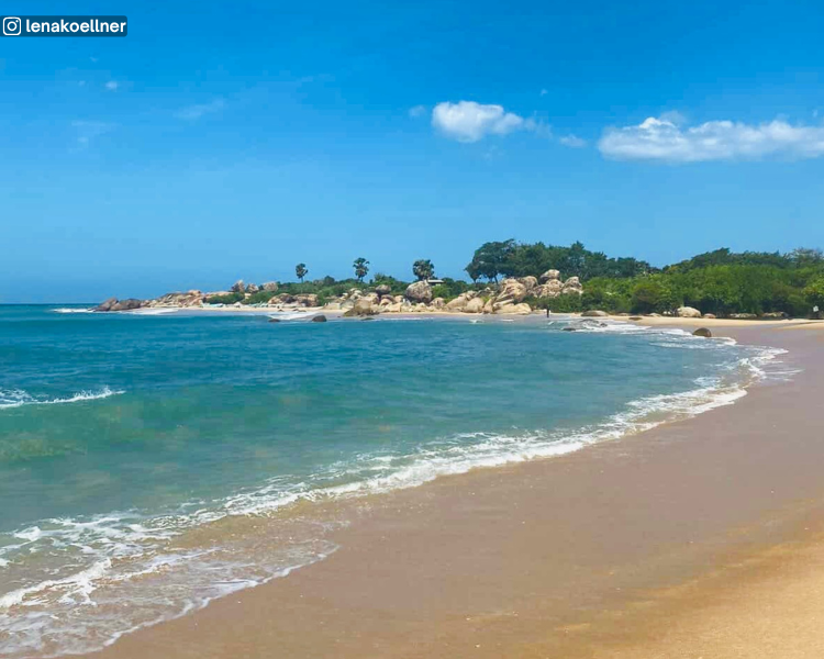Sea and beach view with a distant rocky area and tree line at Peanut Farm Beach near Arugam Bay, Sri Lanka
