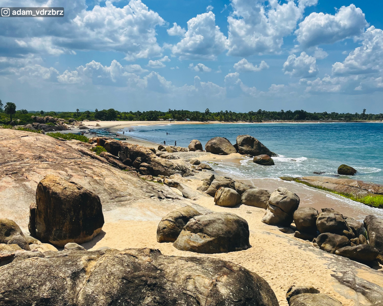 Rocky beach view with sea and distant tree line at Pottuvil Point near Arugam Bay, Sri Lanka