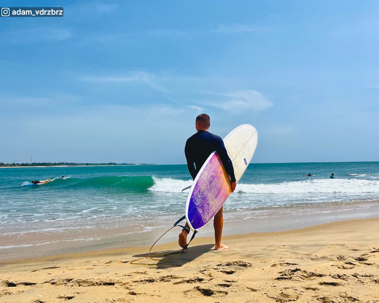 Surfers in the water with one surfer at the shoreline at Pottuvil Point near Arugam Bay, Sri Lanka