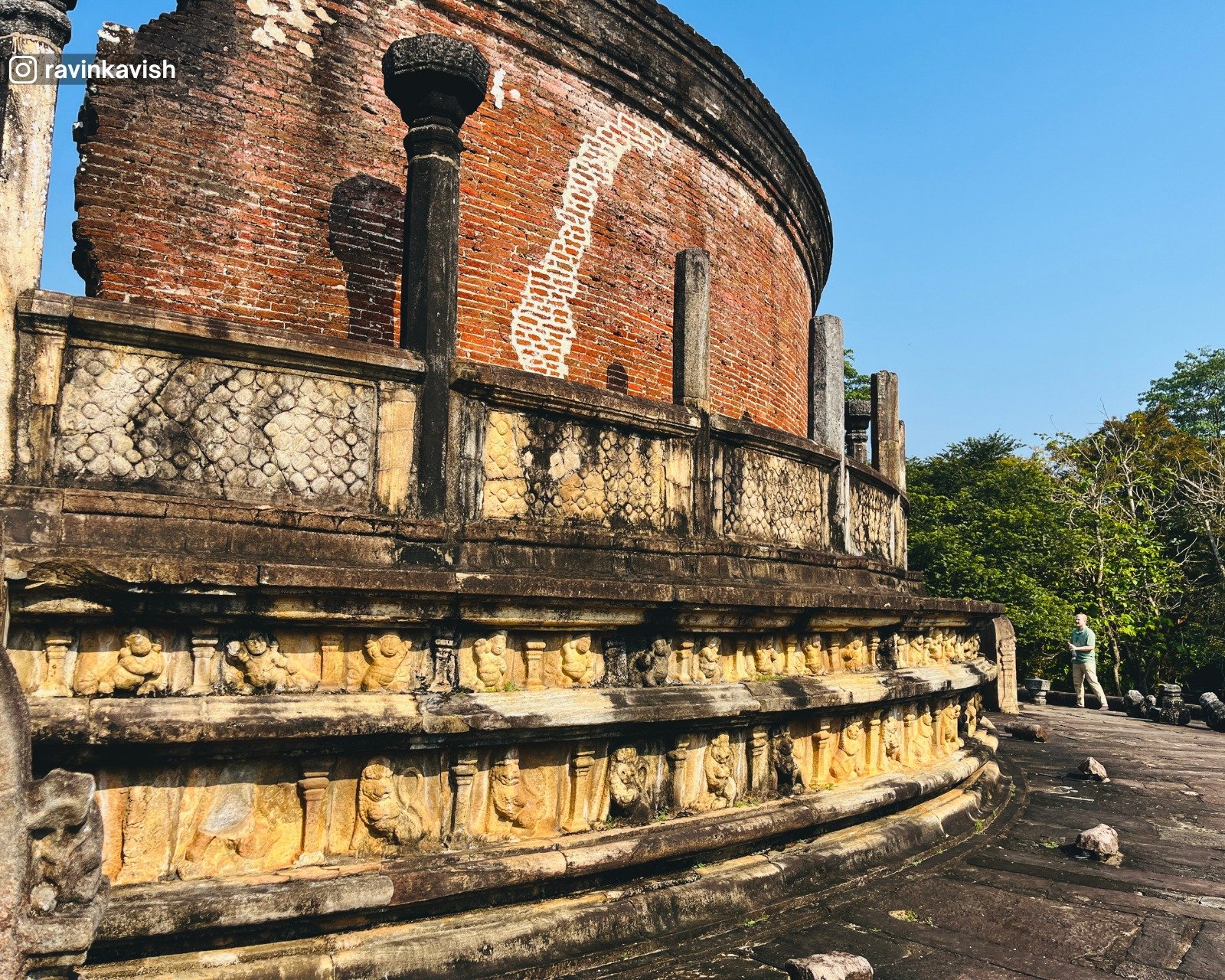 Exterior view of Polonnaruwa Vatadage showing circular stone platform, entrance staircase with moonstone and guard stones, and surrounding pillar ruins under open sky