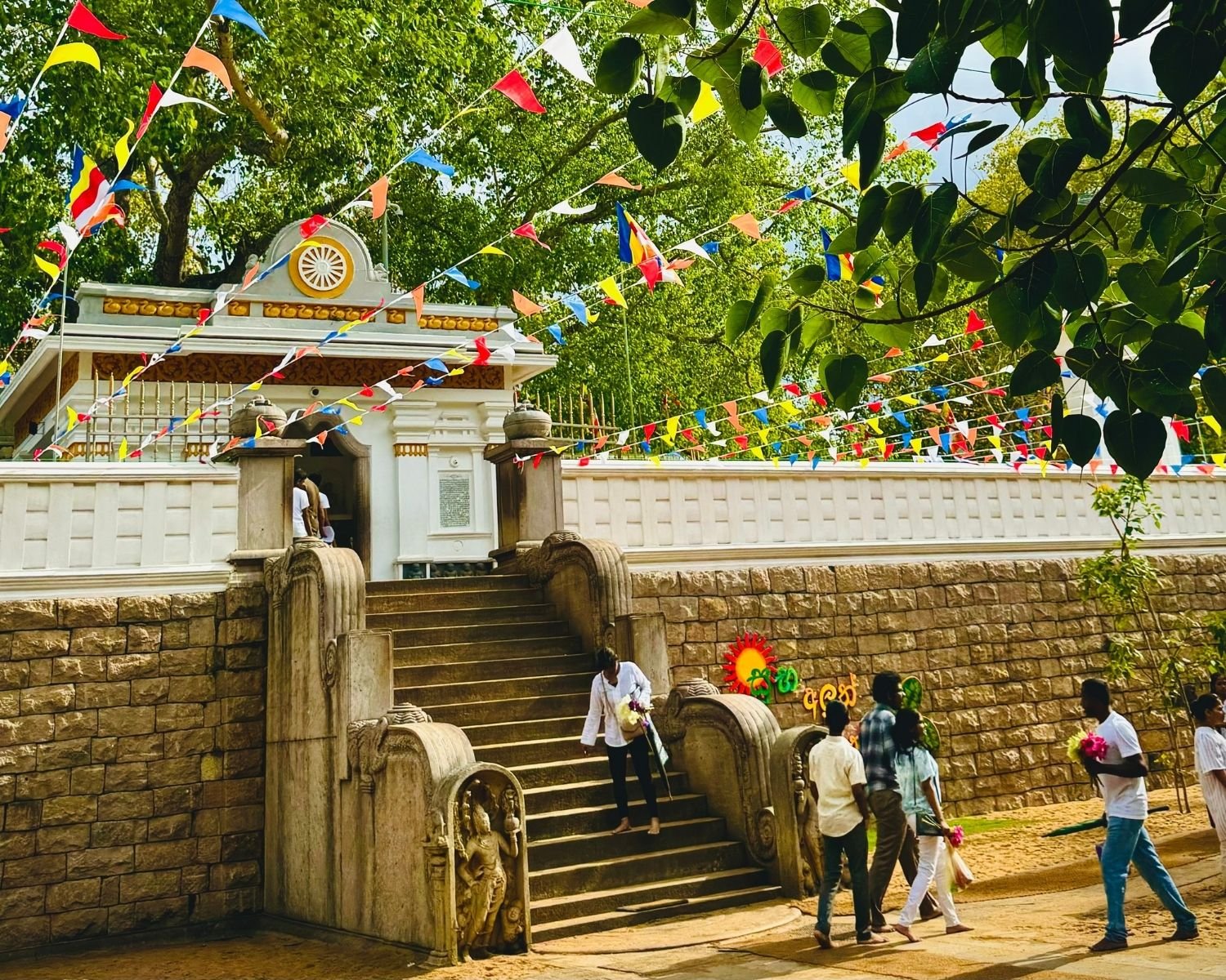 Muragala guardstones and Dharma Chakra arch at Jaya Sri Maha Bodhi stairway with festive bunting in Anuradhapura
