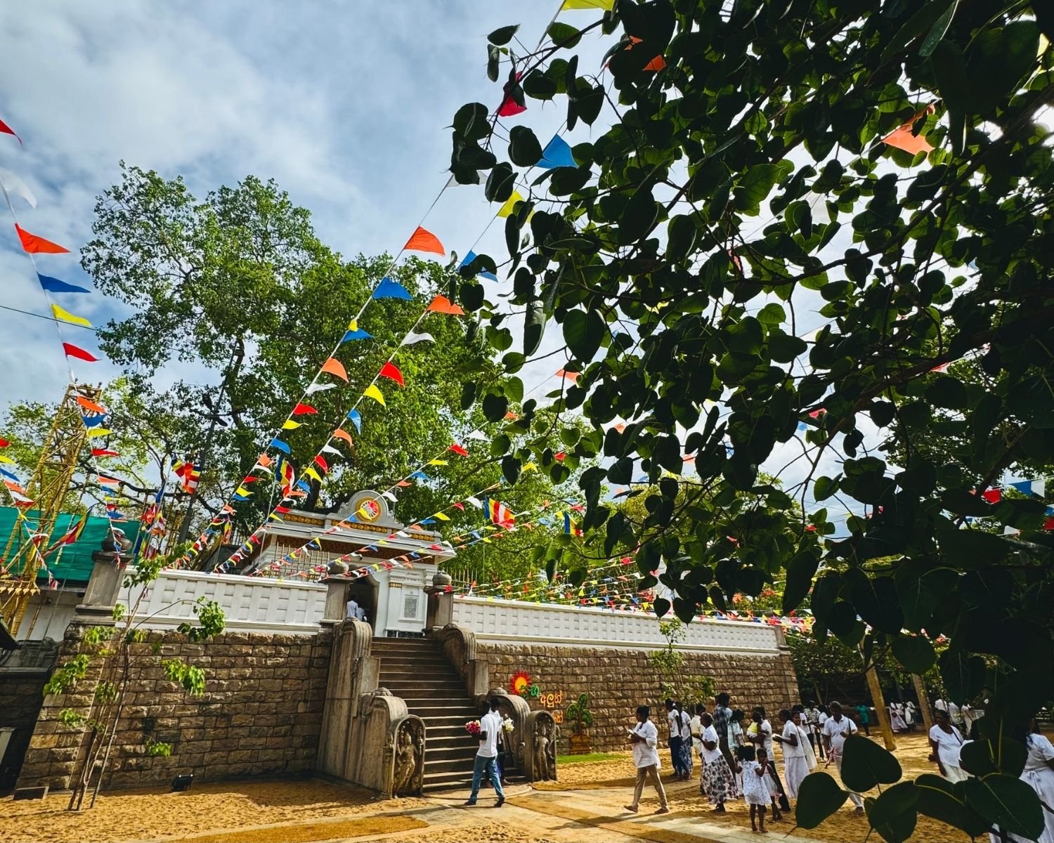 Jaya Sri Maha Bodhi in Anuradhapura decorated with Buddhist flags and Muragala guardstones framed by Bo leaves