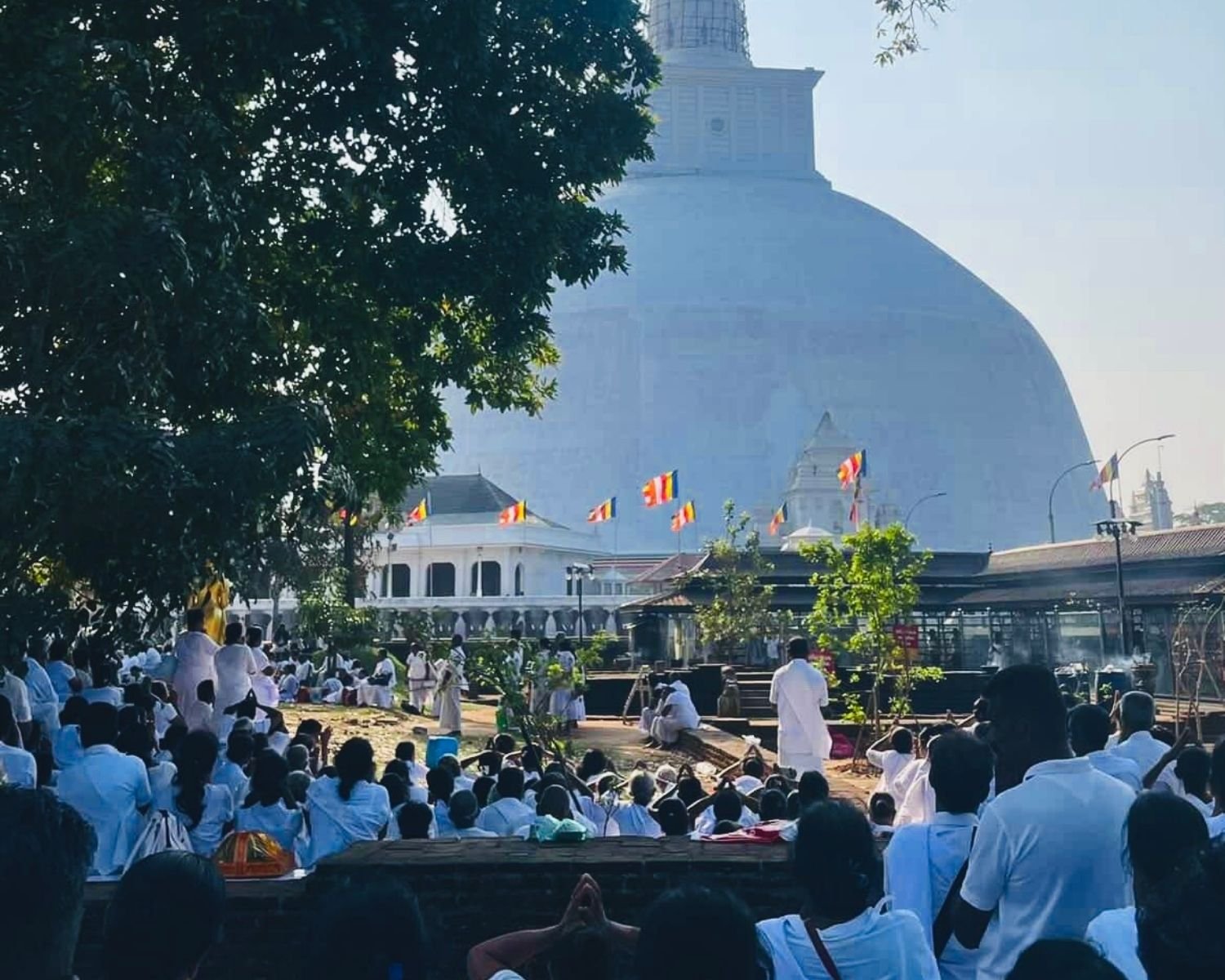 Devotees in white worship with incense smoke during Poya day at Ruwanwelisaya stupa maluwa in Anuradhapura