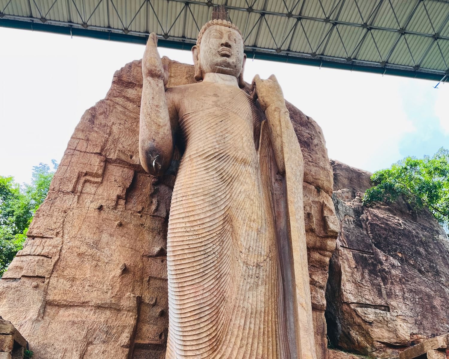 Low-angle view highlighting the Asisa Mudra blessing gesture and robe details