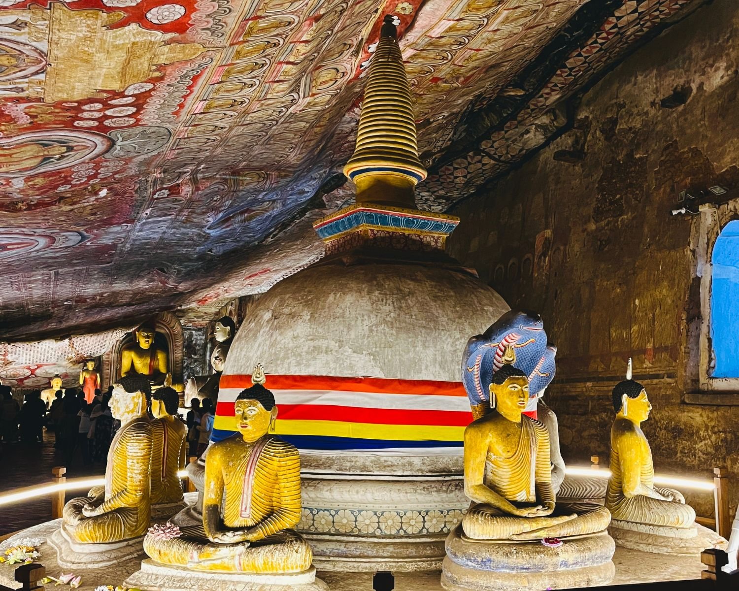 Seated Buddha statues arranged around a large cave stupa