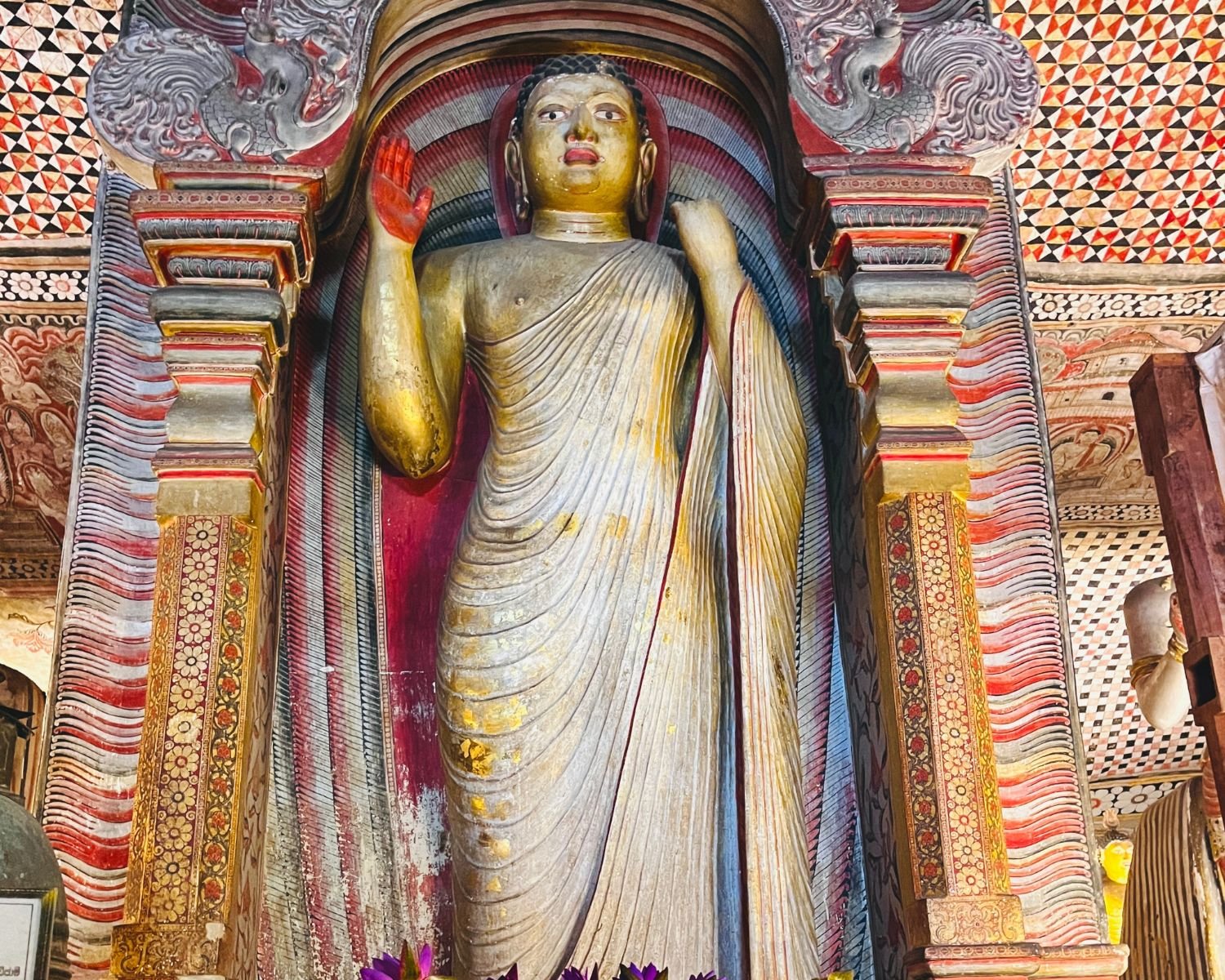 Standing Buddha statue within a sculpted shrine arch