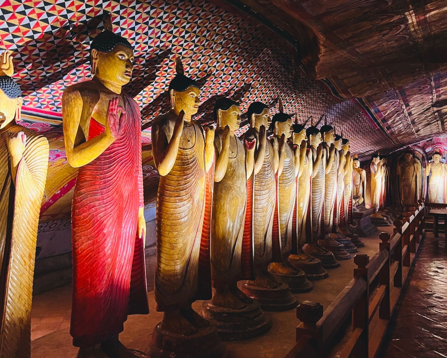 Standing Buddha statues beneath patterned ceiling murals