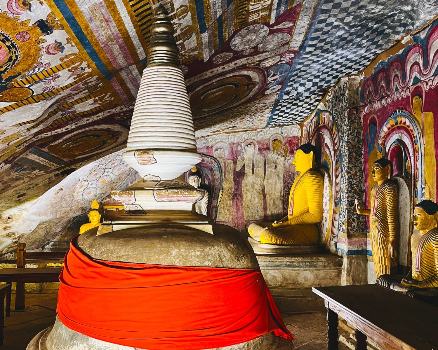 Red-draped stupa beneath painted ceiling murals