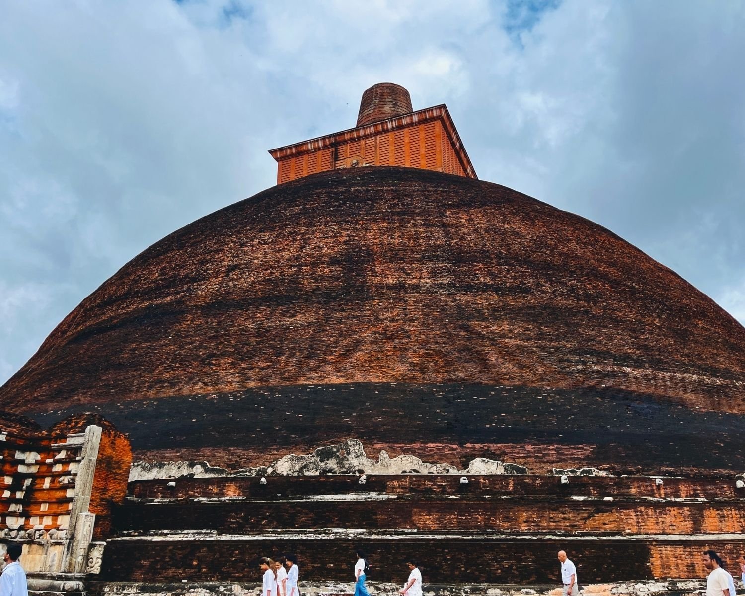 Jetavanaramaya south face with massive brick dome, square harmika, broken spire, and devotees at base