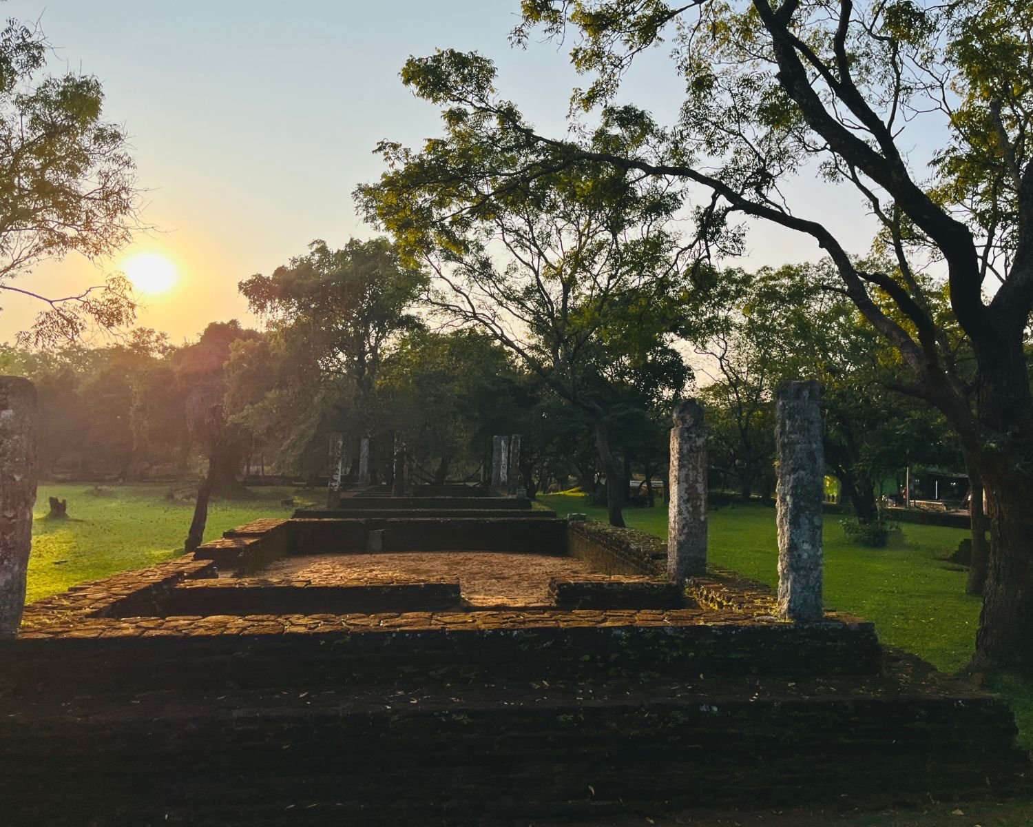 Moss-covered brick foundations and stone pillars of monk’s residence in Alahana Pirivena at sunset