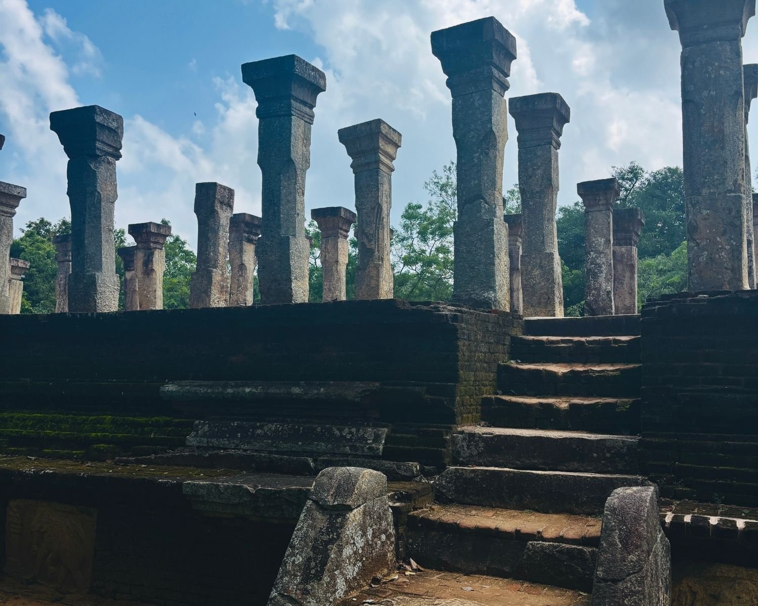 Low angle view of Council Chamber of Nissanka Malla showing stone steps, guard stones, and tall pillars against sky
