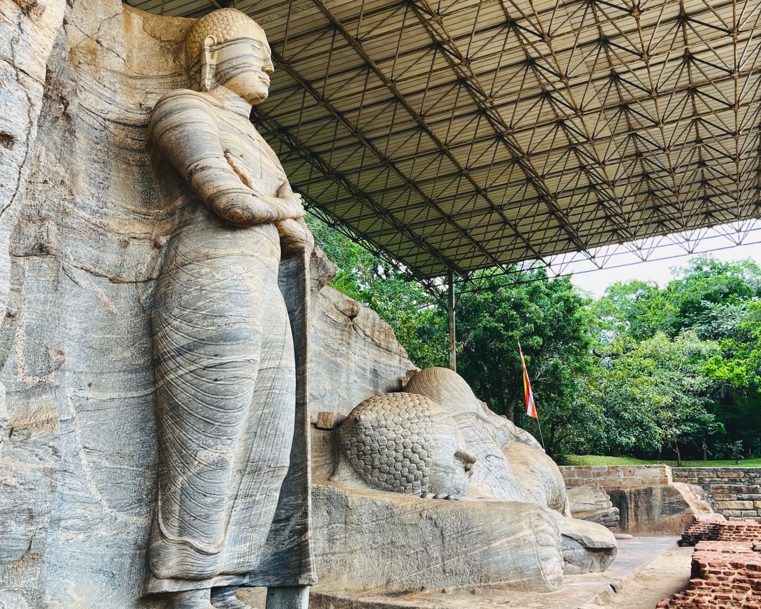 Standing Buddha beside reclining Buddha carved into granite rock face at Gal Vihara
