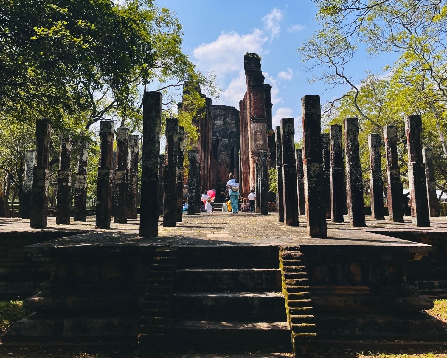 Stone pillars of Hevisi Mandapaya Drum Pavilion framing Lankatilaka Image House brick walls in Alahana Pirivena