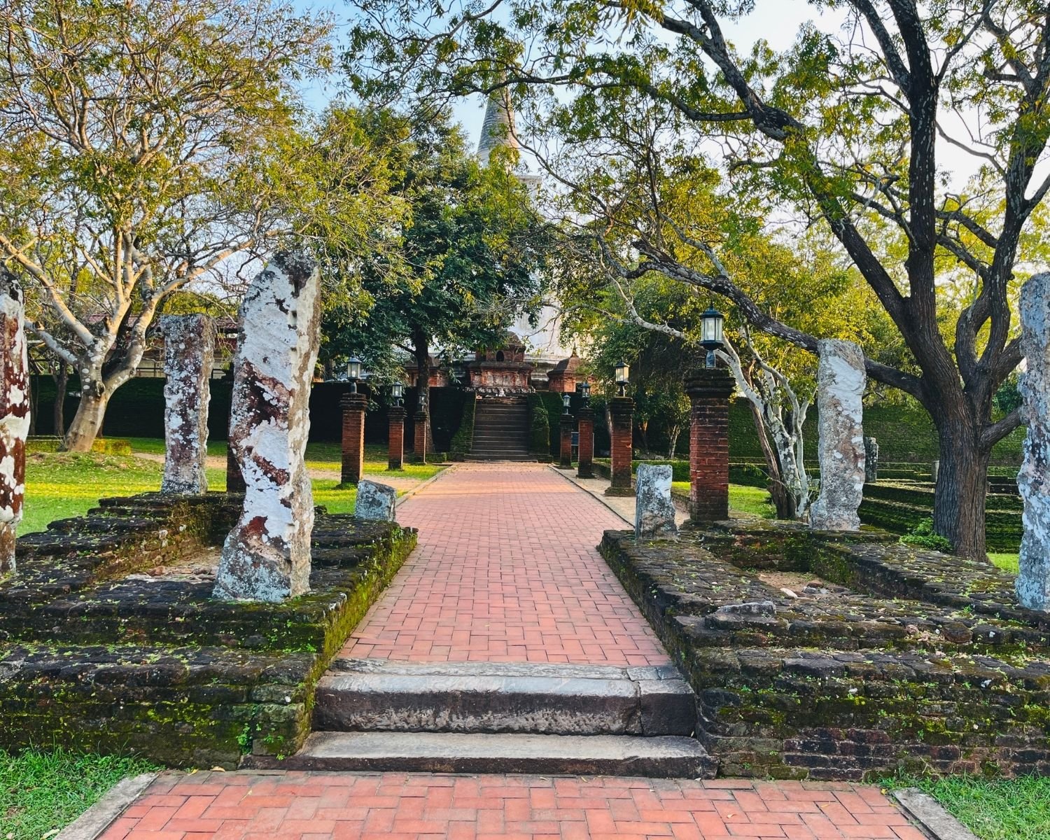 Brick pathway with ancient granite pillars and modern lamp posts leading to Kiri Vehera dagoba