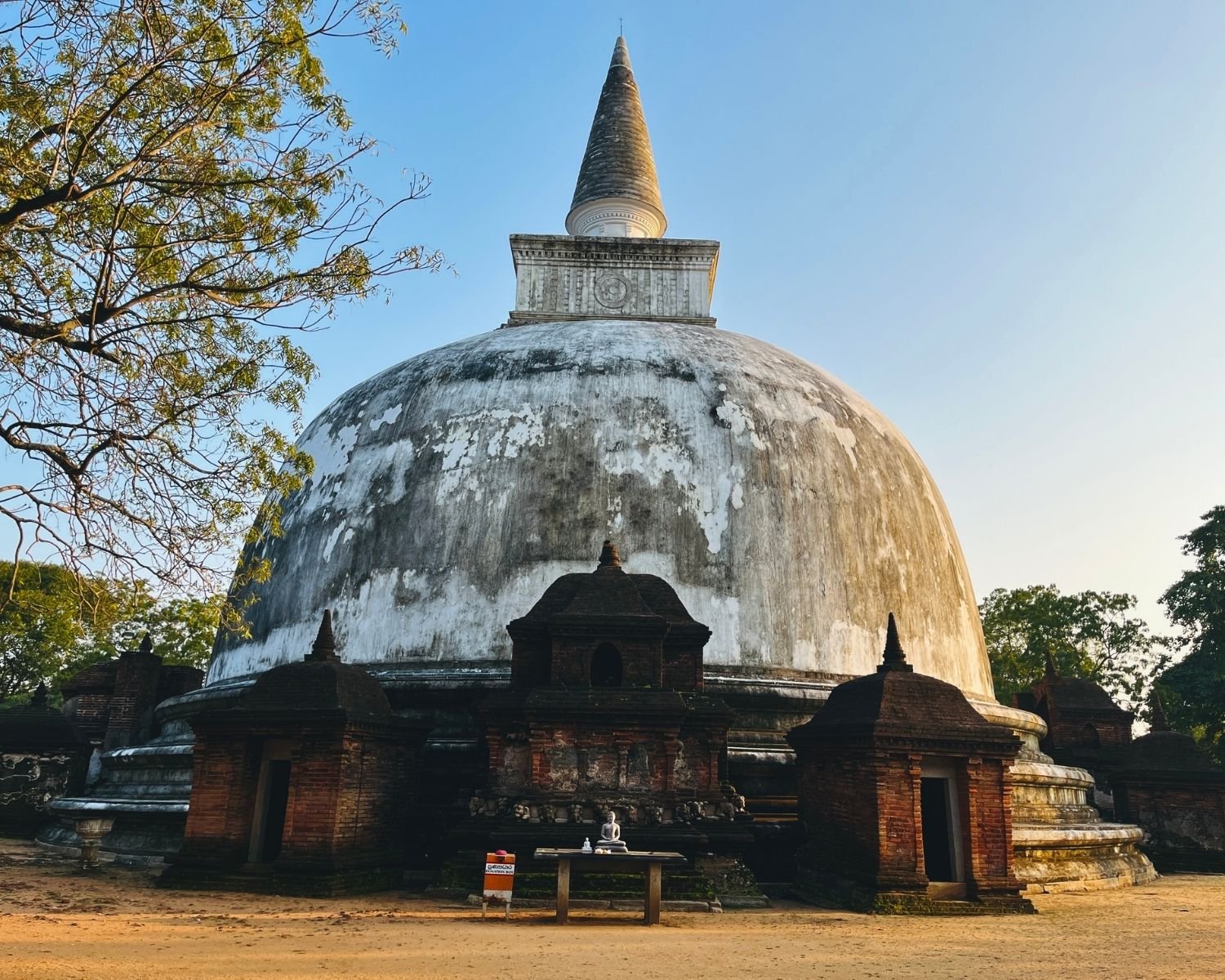 Front view of Kiri Vehera white dagoba with brick vahalkada shrine at golden hour in Alahana Pirivena