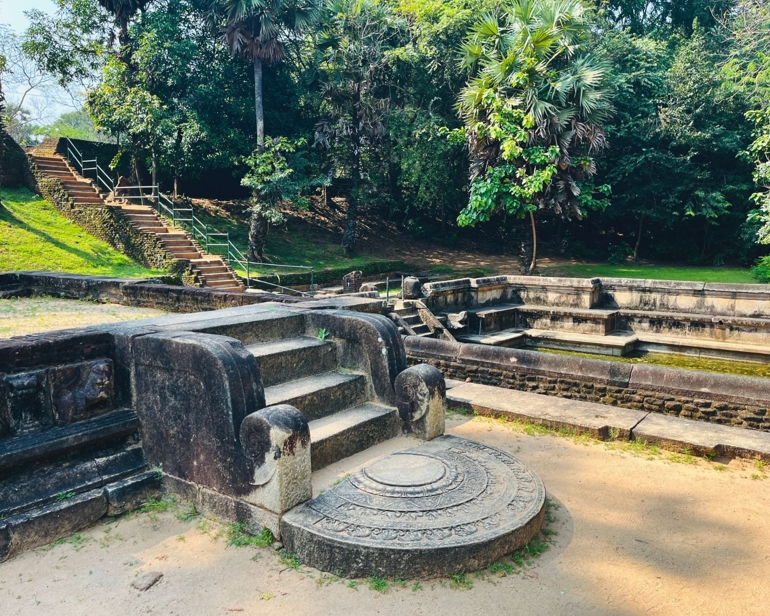 Moonstone and stone steps beside Kumara Pokuna with carved balustrades