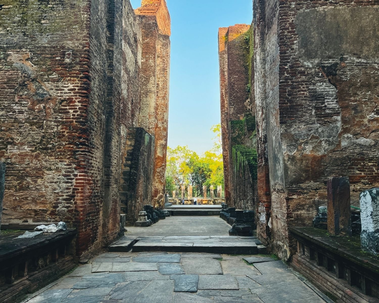 View looking out through tall brick walls of Lankatilaka toward entrance with trees and open sky