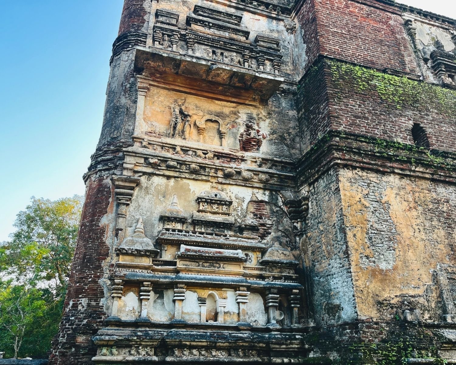 Northeast corner of Lankatilaka north wall showing brick pilaster, stucco figure, and miniature shrine reliefs