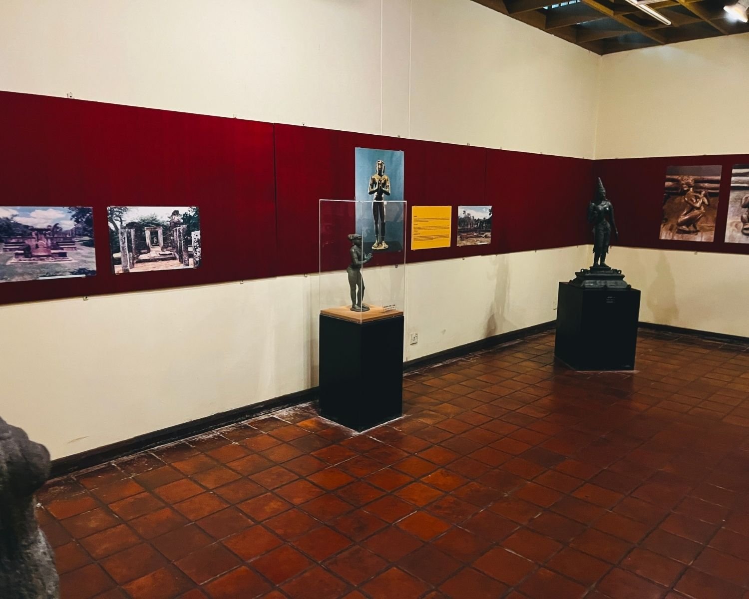 Indoor gallery at Polonnaruwa Museum showing ancient stone sculptures and seated Buddha image