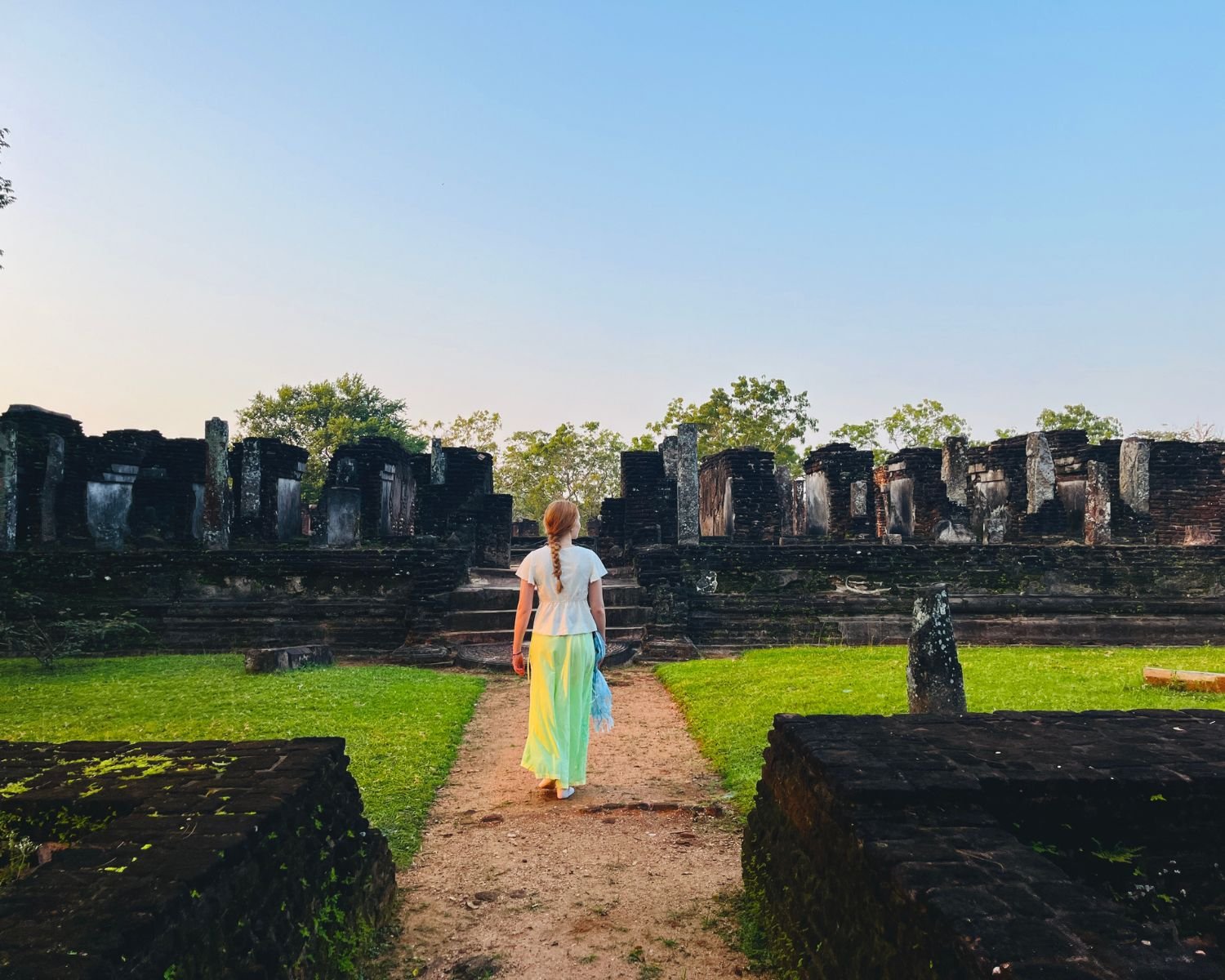 Visitor in white walks toward steps of Baddhasima Prasadaya south face with brick ruins