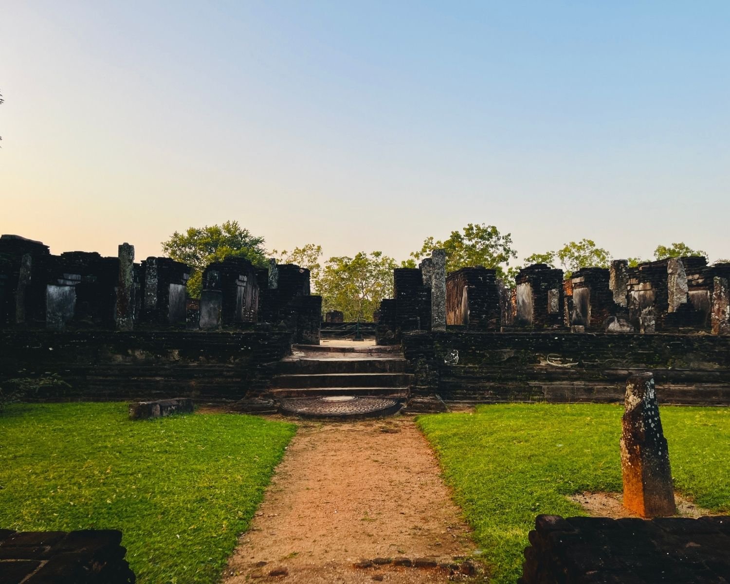 South face of Baddhasima Prasadaya with steps, moonstone, and brick ruins in evening light