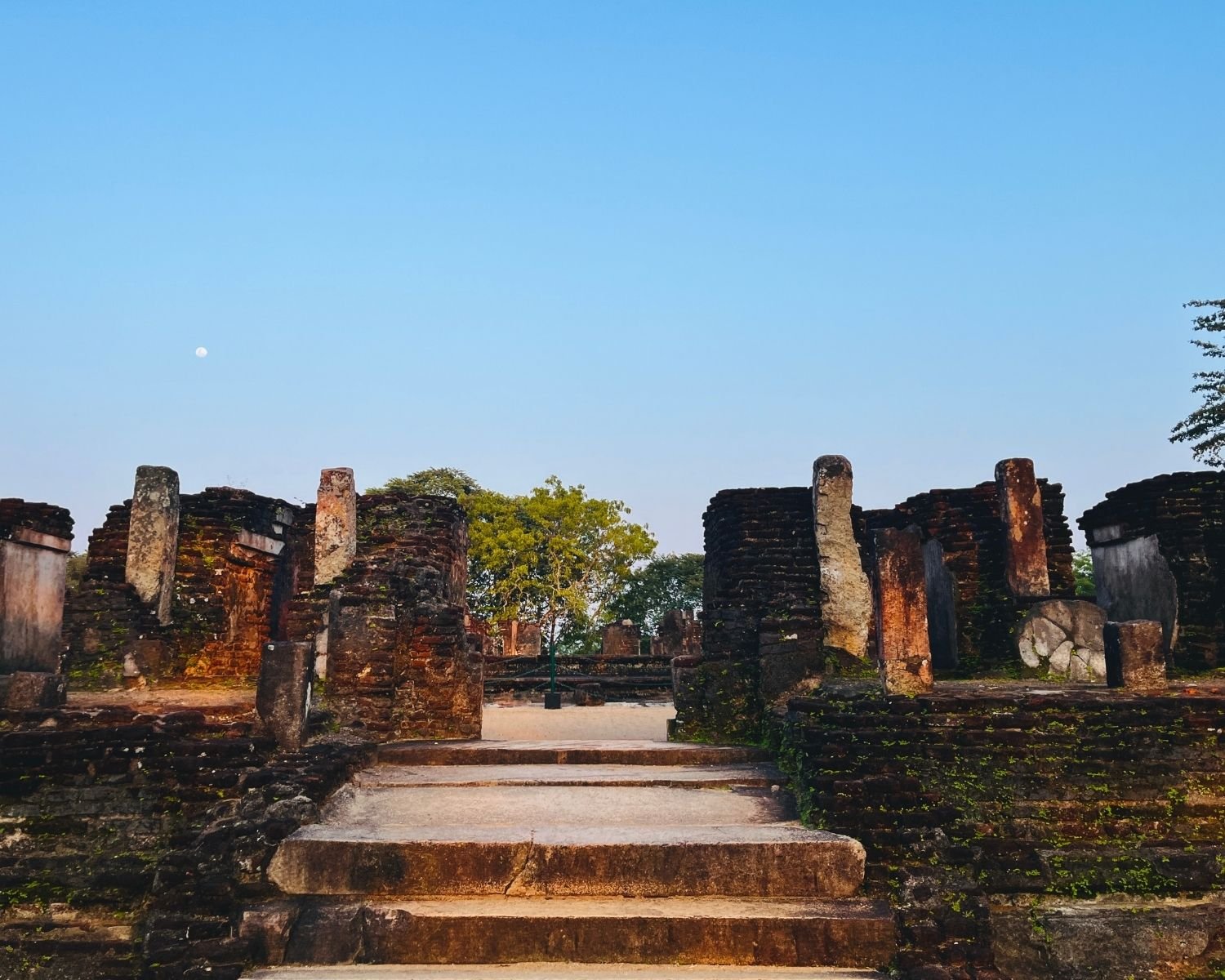 Steps to west entrance of Baddhasima Prasadaya with brick ruins and stone pillars at dusk