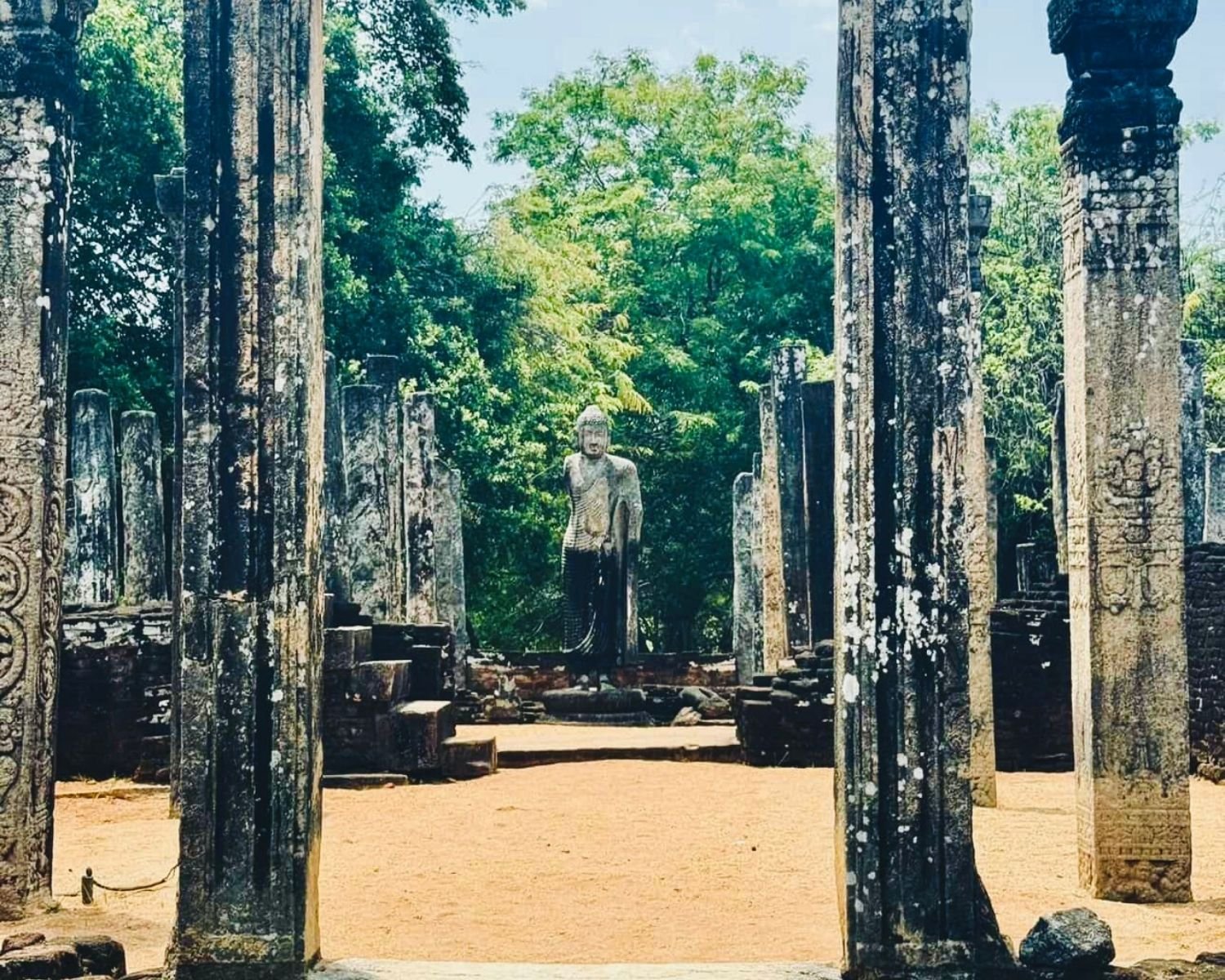 Central standing Buddha statue inside Atadage framed by carved stone pillars