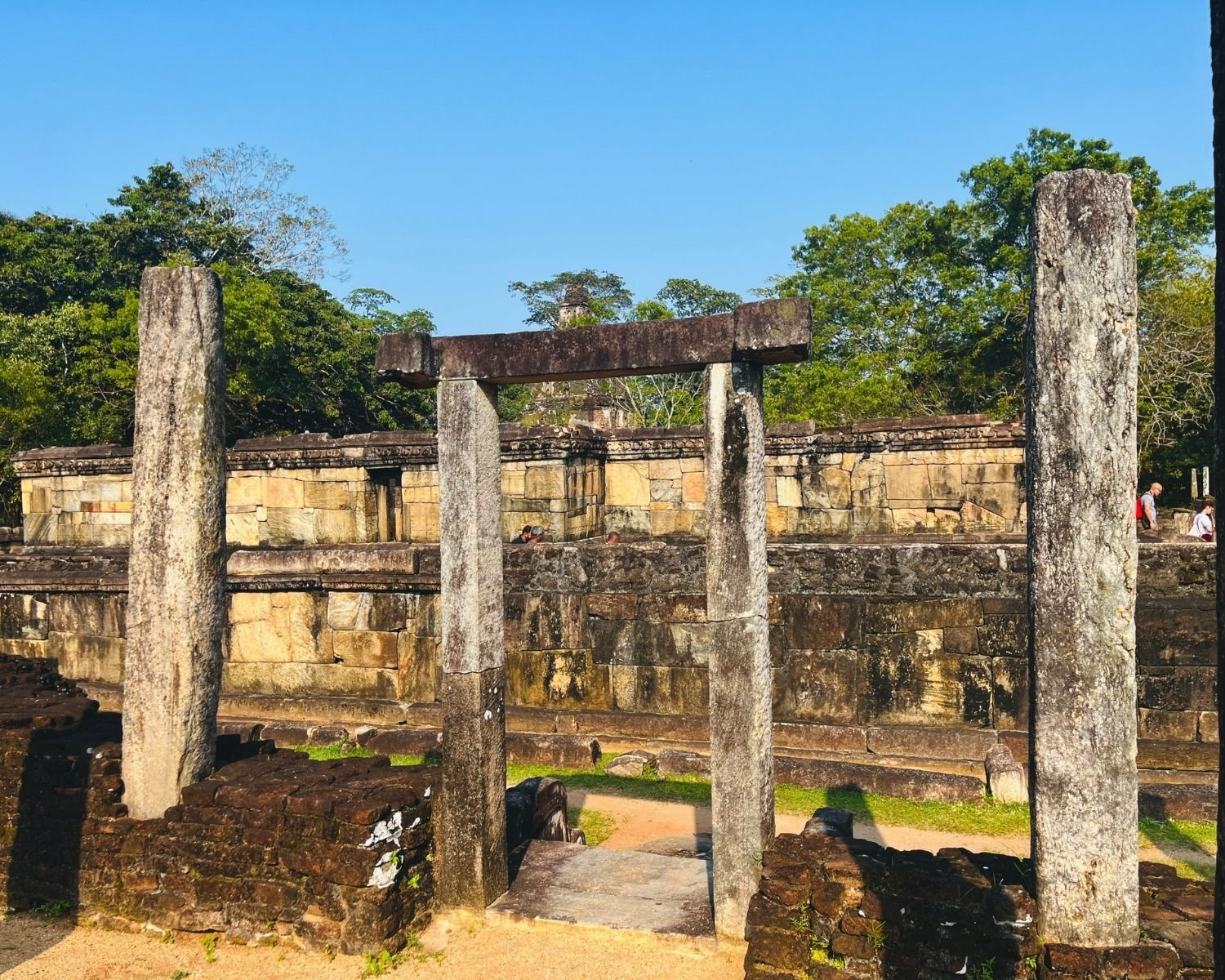 View through stone doorway of Hatadage with stone pillars, carved walls, and Satmahal Prasada beyond