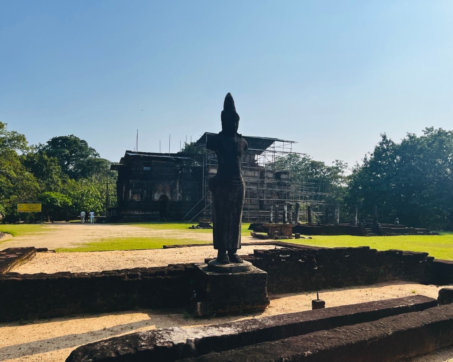 Headless Bodhisattva statue in Sacred Quadrangle with Thuparama Image House under scaffolding behind