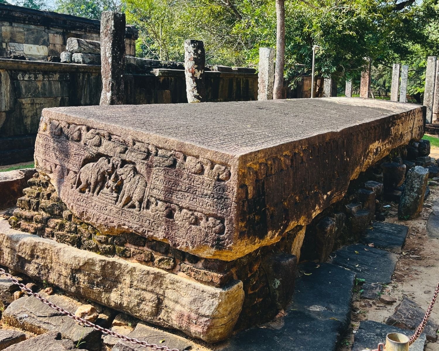 Side view of Gal Potha Stone Book with dense inscriptions and carved edge, Hetadageya pillars behind