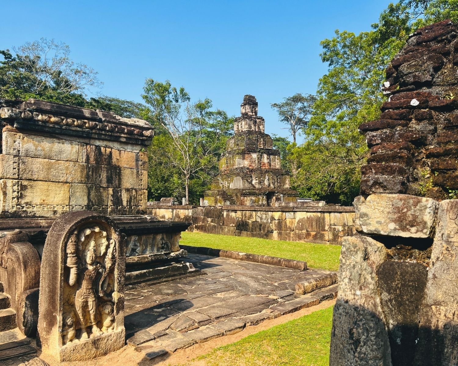 Inscribed stone walls of Hatadageya relic house with Satmahal Prasada tower behind in Sacred Quadrangle