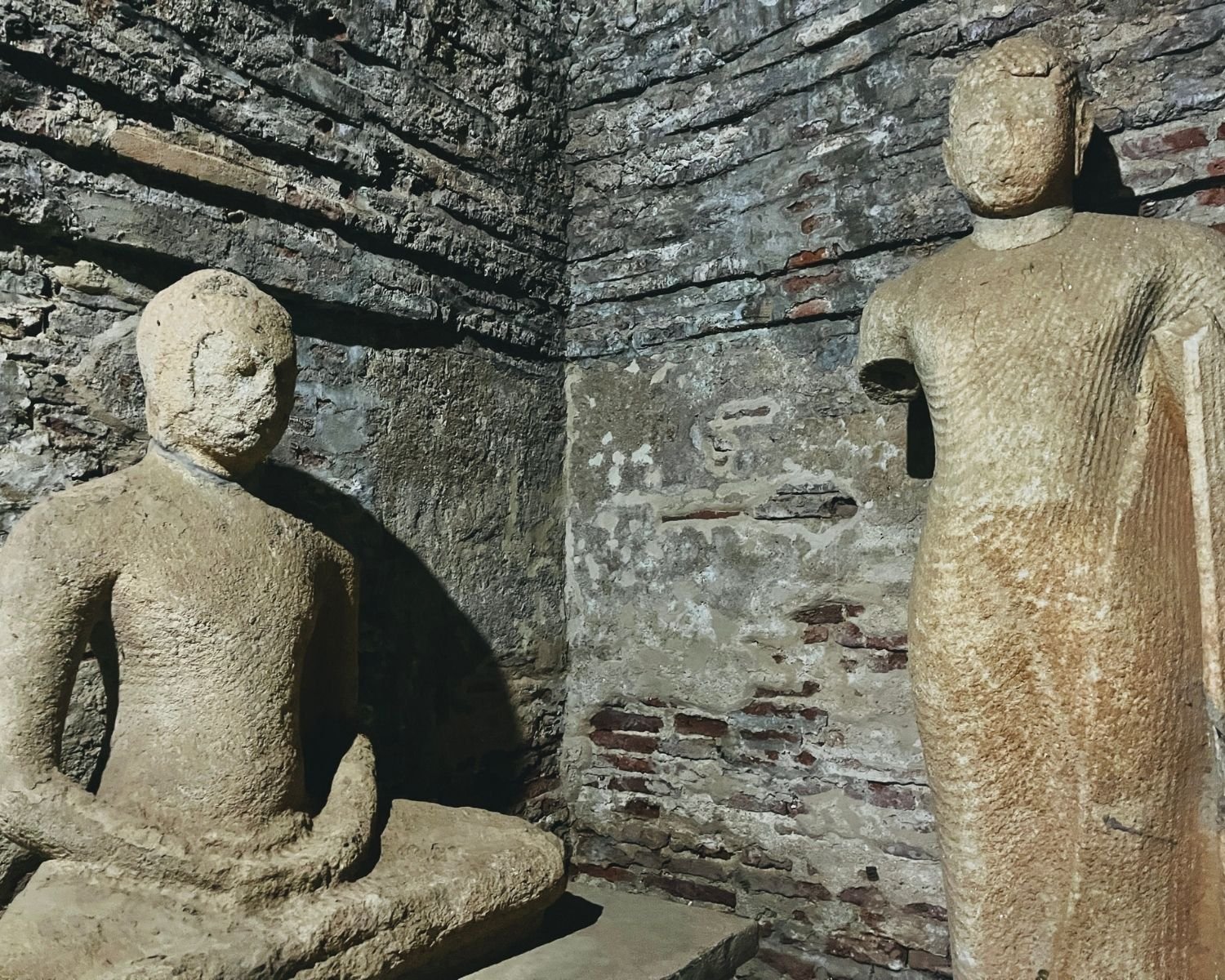 Seated and standing Buddha statues in brick corner chamber of Thuparama Image House