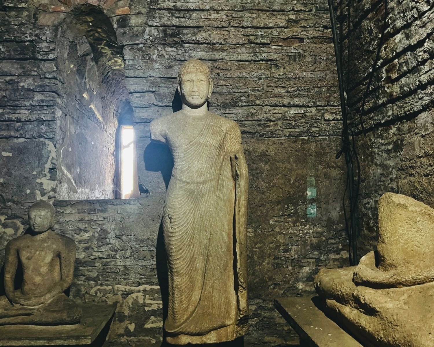 Interior of Thuparama Image House showing standing Buddha flanked by seated Buddha images in brick chamber